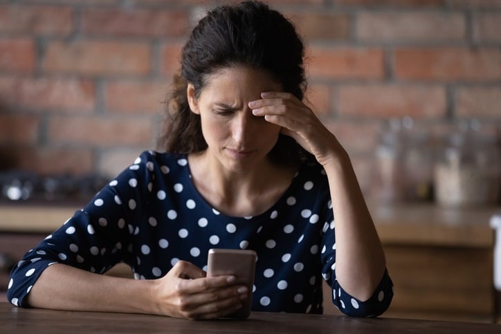 unhappy woman looking at her cell phone screen