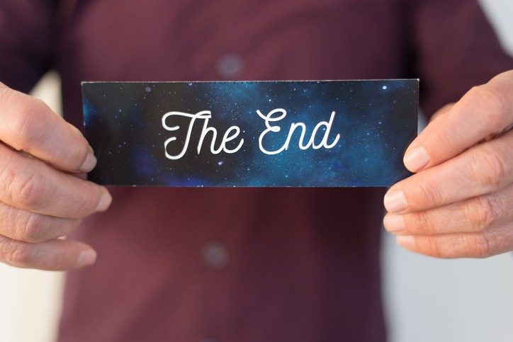 Man holding a card reading "the end"