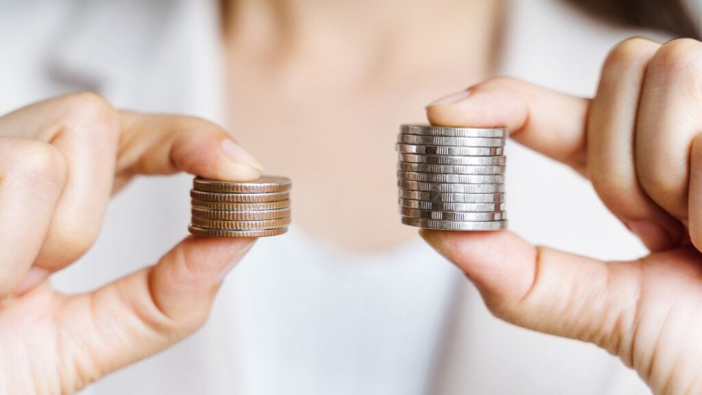 Uma comparação de preços por meio de diferentes pilhas de moedas mantidas em cada mão.