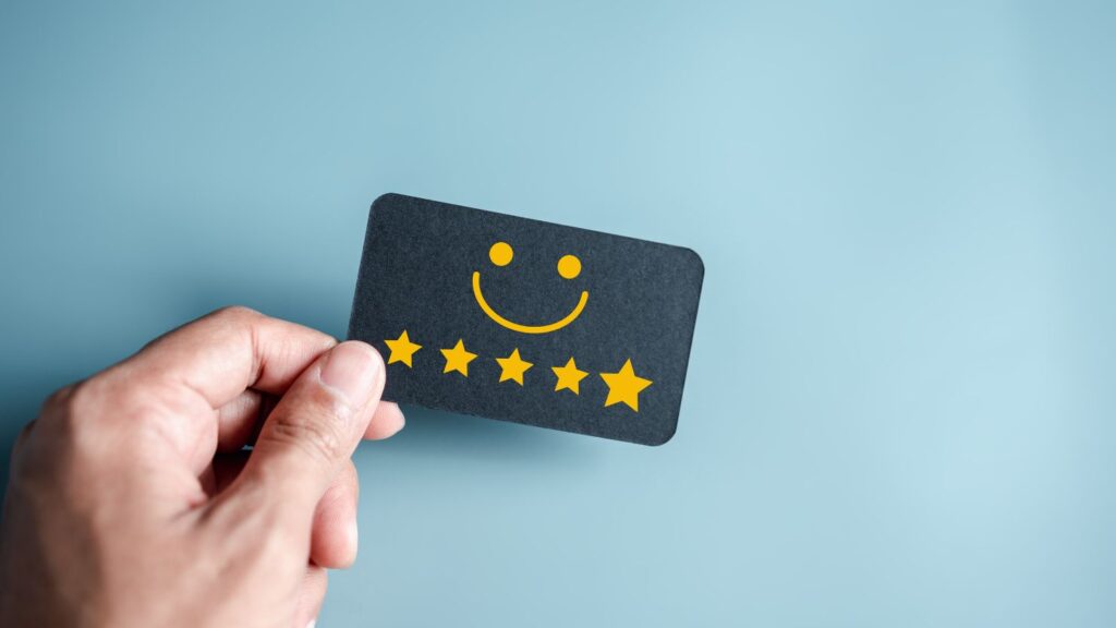 a hand holding out a card with a smiley symbol and 5 stars.