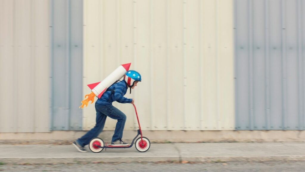 Ein Junge fährt mit seinem Roller, während er ein künstliches Jetpack trägt.