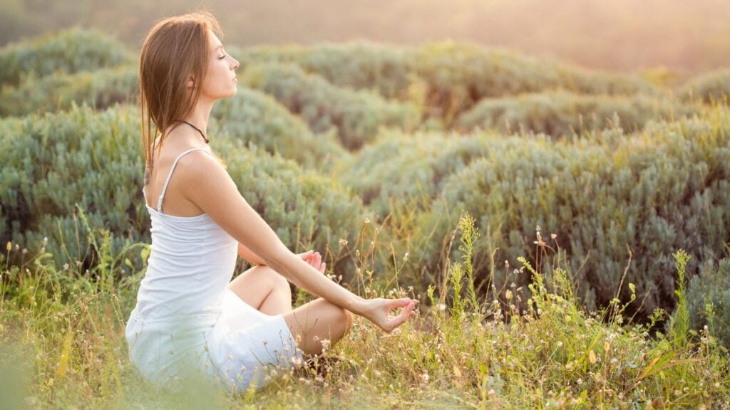 a woman meditating in a field