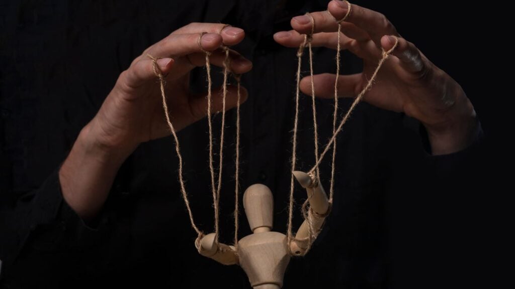hands manipulating a wooden puppet