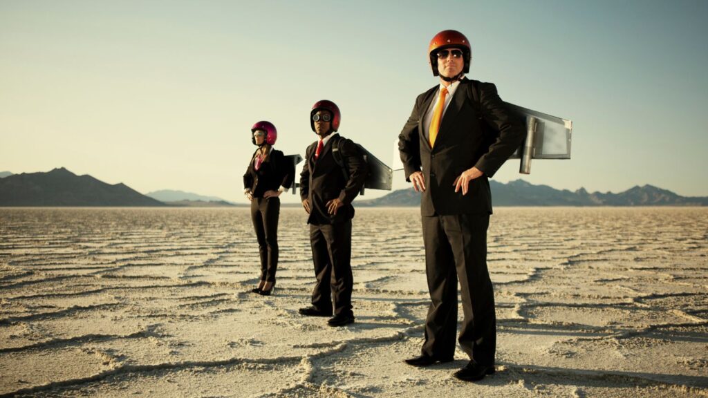 Three men representing a small business team with makeshift rockets attached on their back. 