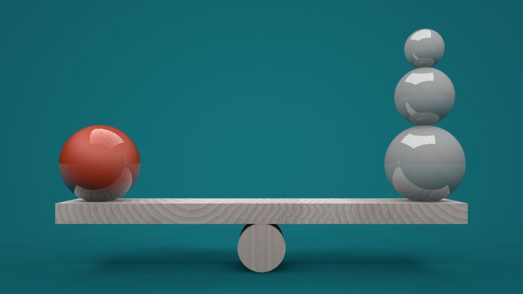 Balls perfectly balanced on a makeshift wooden weighing scale to represent balance
