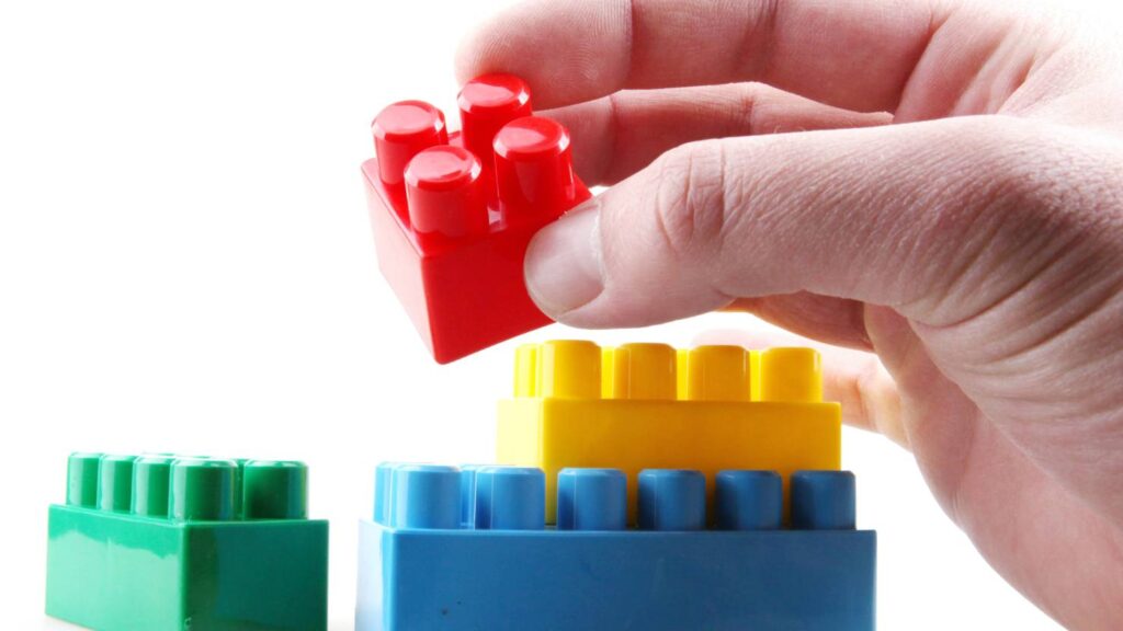 a child's hand assembling 4 lego blocks