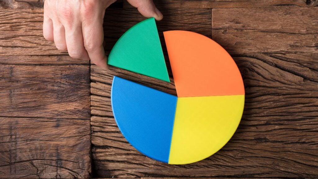 A photo of a man's hand taking a piece of a pie chart to symbolize market share.