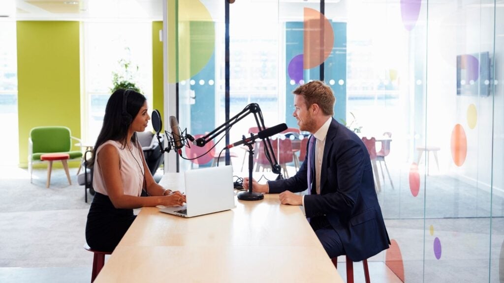 Una joven entrevista a un invitado en un estudio para un podcast