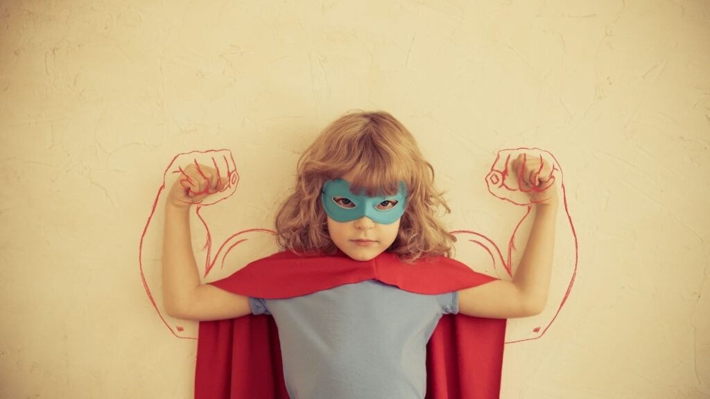 garota em uma fantasia improvisada de super-herói flexionando seus músculos.