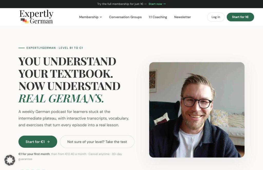 Expertly-German | MemberPress Hero section promoting German learning: bold headline on the left and a rounded video portrait of a smiling man on the right.