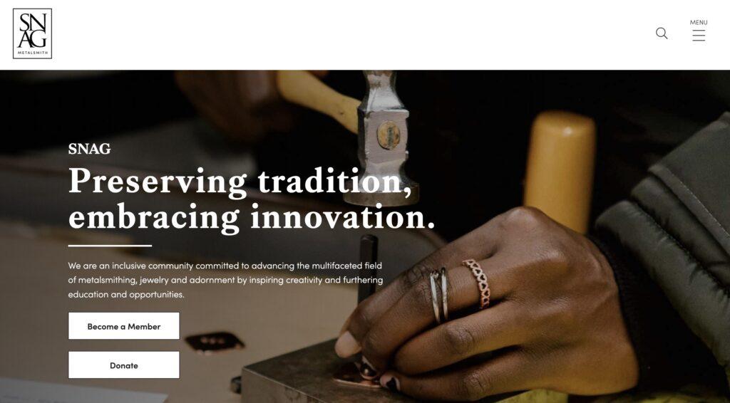 Society of North American Goldsmiths Homepage Screenshot | MemberPress SNAG Metalsmith hero image showing hands at work with a stamping tool and the slogan 'Preserving tradition, embracing innovation'.